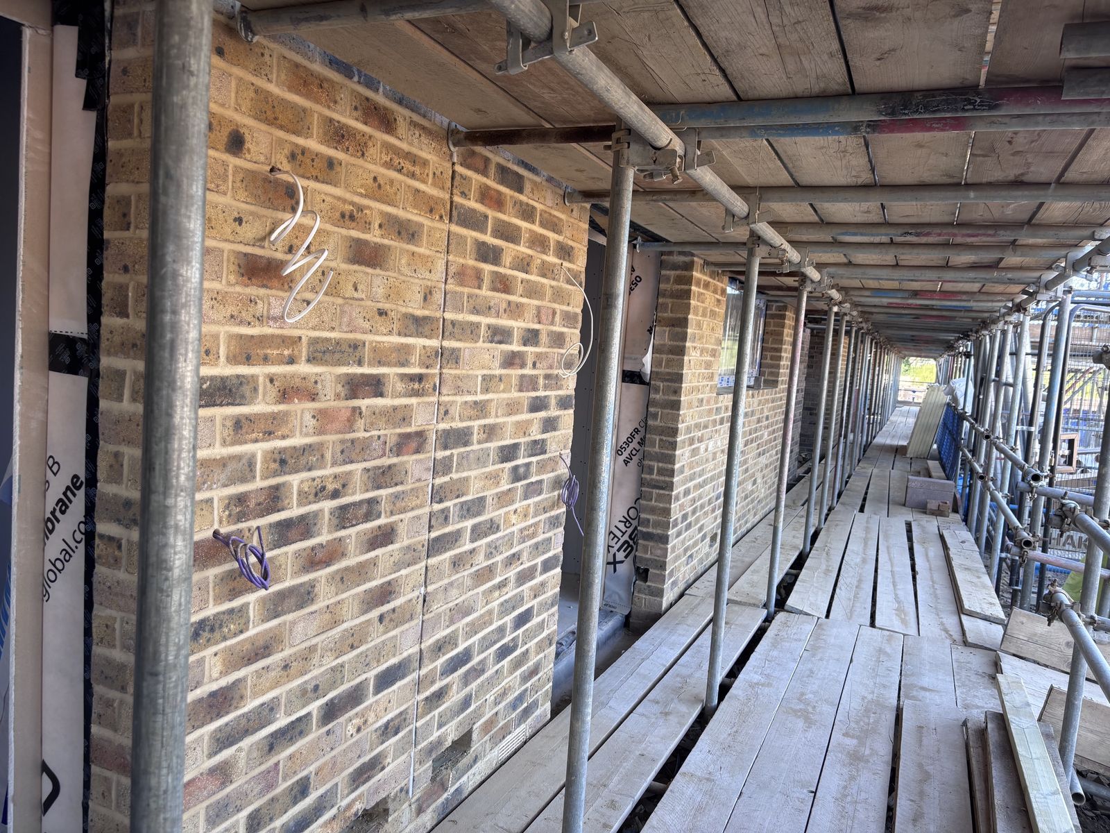 Long scaffold walkway beside completed brickwork at Tipner East